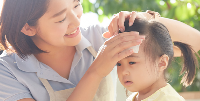 子供の熱を測る保育士