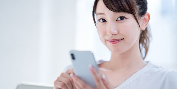 スマホを持って微笑む女性