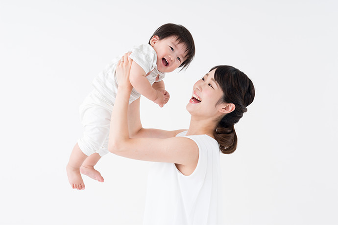 赤ちゃんを抱える笑顔の女性を写した画像