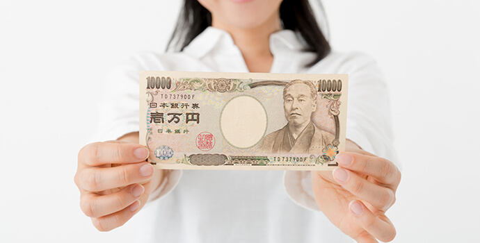 笑顔で1万円札を見せる女性