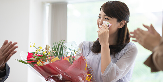 花束を持って涙ぐむ女性保育士